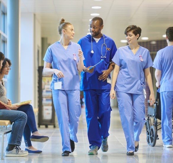 Three medical personal walking in a hospital hallway talking together