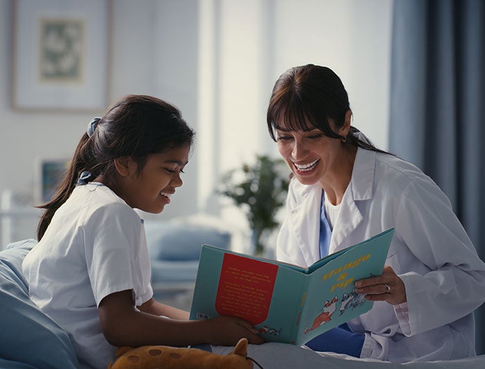 A female doctor reads to a smiling girl
