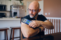 Do Digital Diabetes Management Tools Deliver Intended Value? A man with diabetes checks his blood glucose level through a continuous glucose monitor with a mobile app on his phone.