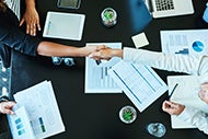 Clinical staff and patient shaking hands across a table