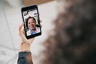 Telehealth at the Center of New Human Primary Care Plan: Image of hand holding a mobile phone during a video chat with a clinician.