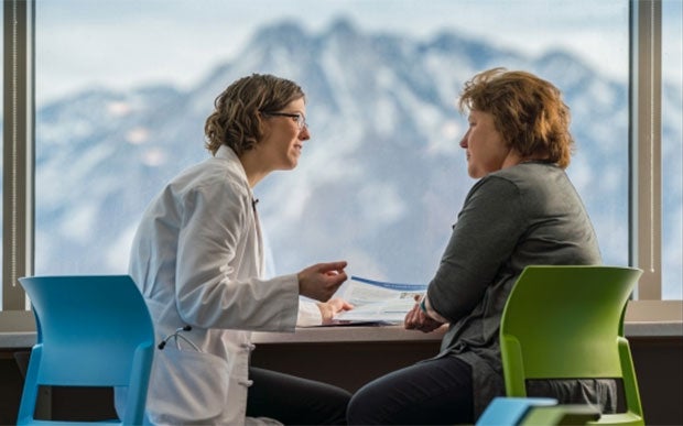 Market Expands for Teaching Value-Based Care Imperatives. Clinician discussing medical literature with a patient with mountains in the background.
