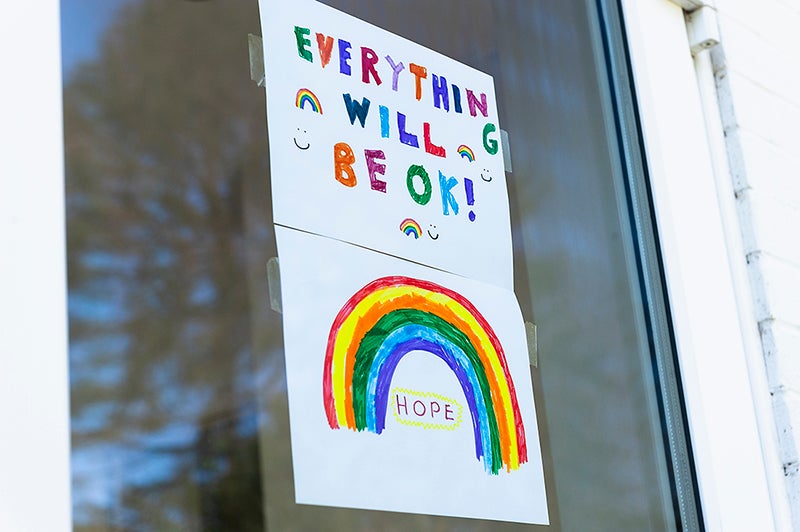 Child's rainbow colored drawing in window says "everything will be ok!"