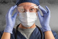 Providers Team Up to Expand PPE Production. A clinician in mask, gloves, and goggles.