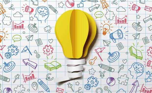 Shared Risk May Be Key to Future Growth Opportunities. A light bulb made out of paper on graph paper covered with business and productivity icons.