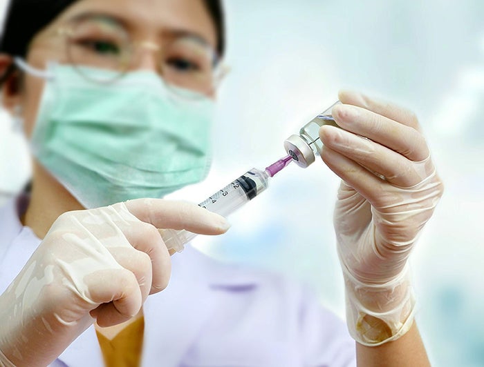 female health worker draws vaccine into a syringe for an injection in this stock photo