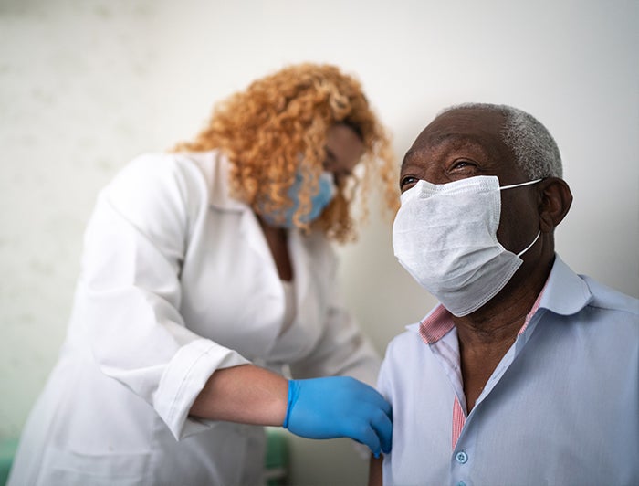 female health worker administers an injection to an elderly male patient in this stock photo