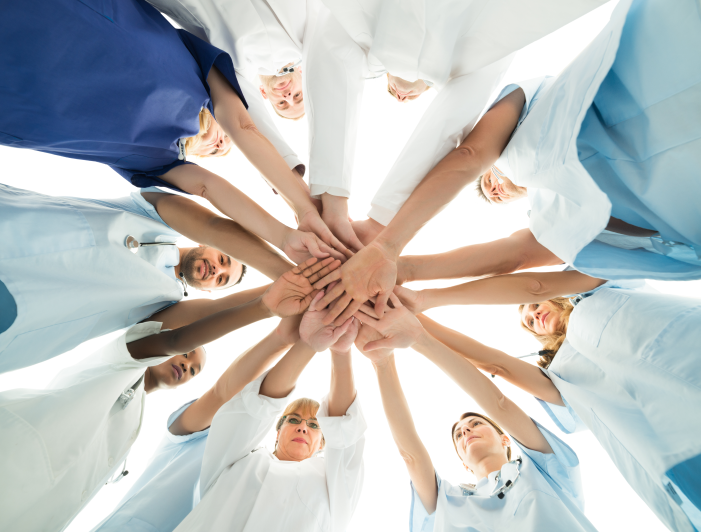 Looking up under hands of doctors and nurses in circle together for teamwork