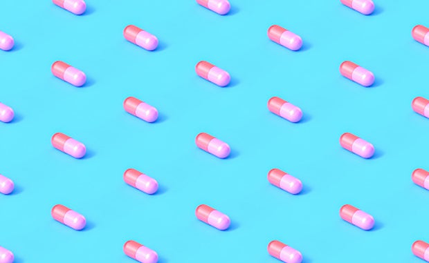Will Startup PBMs Drive Drug Price Transparency? Drug capsules aligned in in straight rows and columns on a blue background.