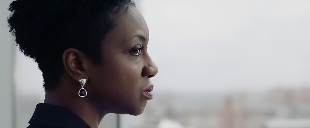 Black woman stares out of high-rise window