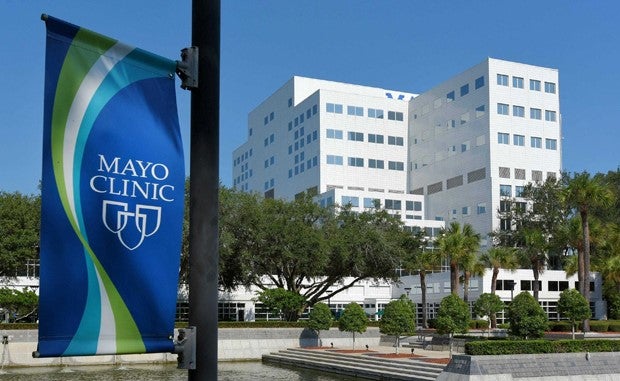 A hotel with a Mayo Clinic banner flying on a lamppost in front of it.