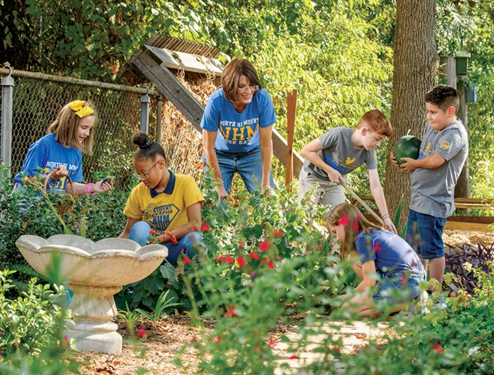 Texas Health Resources. An adult helps a group of children plant a garden.