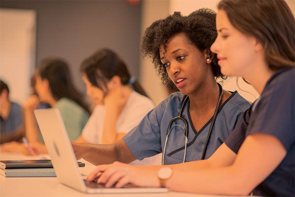 nurses confer over a laptop