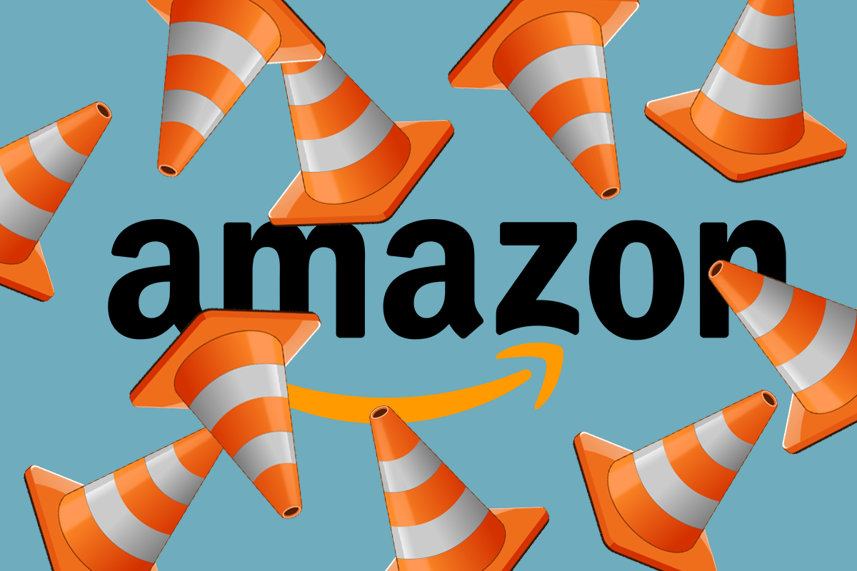 Amazon’s Primary Care Expansion Has Hit a Potential Roadblock. The Amazon logo with a jumble of orange traffic cones in front of it.