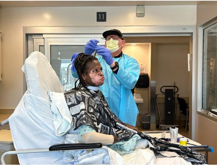 UC Davis employee Aaron Brazier helps amputee Jue Cary with his dreadlocks