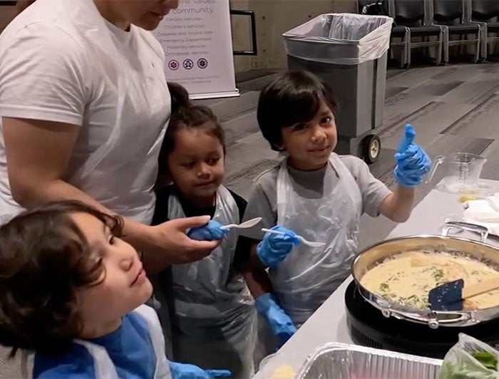 Three children crowd around a cooked dish in the Valley Presbyterian cooking class