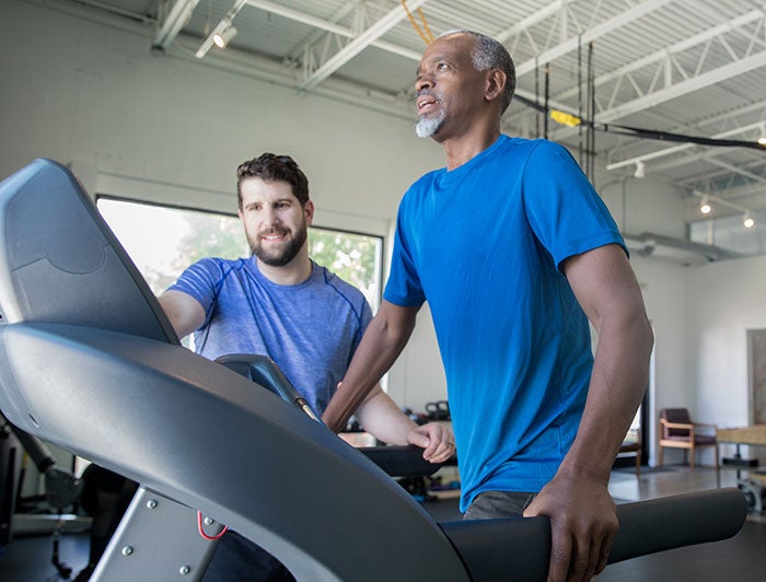 A personal trainer coaches a client on a treadmill