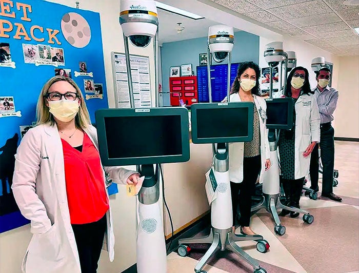 Abington nurses stand lined up next to mobile virtual assistant units