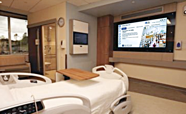 4 Ways New High-Tech Valley Health Facility Will Redefine Patient Experience. A hospital room with a patient bed and a video screen with patient experience information.