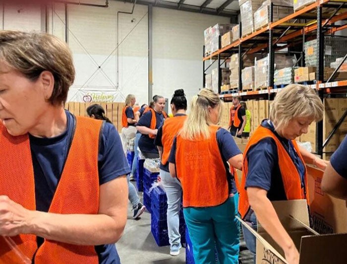 Telling the Hospital Story: Reading Hospital. People wearing orange vests in a warehouse stand packing boxes.