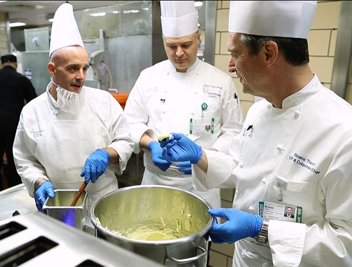 Northwell Health. Three male chefs in Northwell's kitchen gather around a large stock pot
