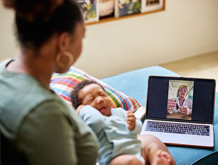 MUSC. Stock image of a black mother holding infant, having a virtual consult with a clinician