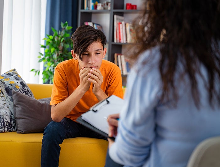 Northern Light Acadia Hospital. Stock image of distraught teen sitting on counselor's sofa