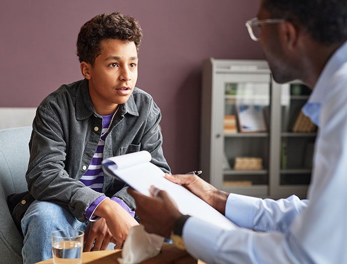 Rady Children's Hospital. A teen boy sits on a sofa talking to a counselor