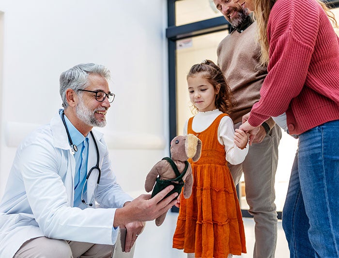 Mercy Hospital. A doctor offers a teddy bear to  a little girl and her parents