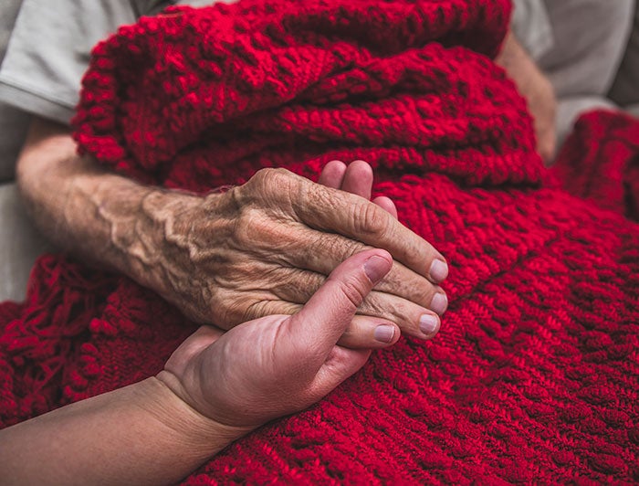 Mon Health Medical Center. A young carer holds the hands of an elderly patient