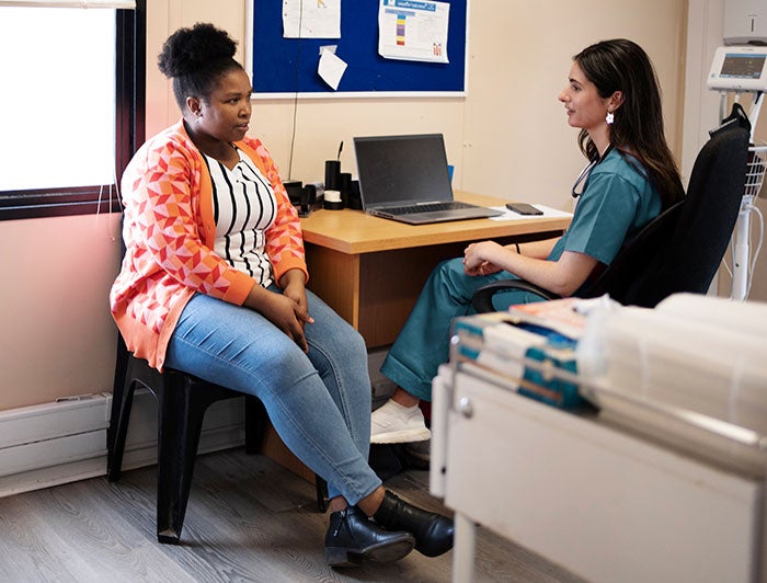 MUSC Health. A female clinician in scrubs sits talking with a female patient in an exam room