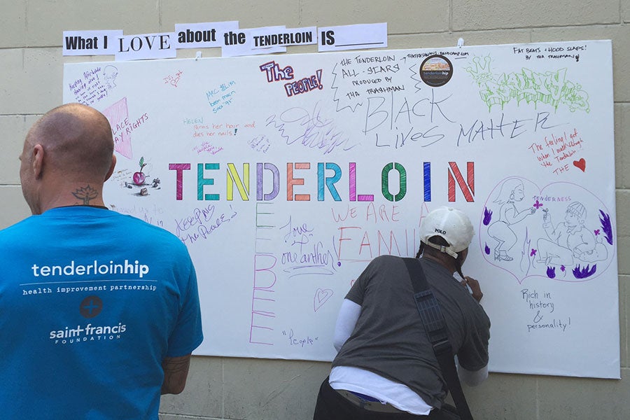 people signing a poster about the tenderloin