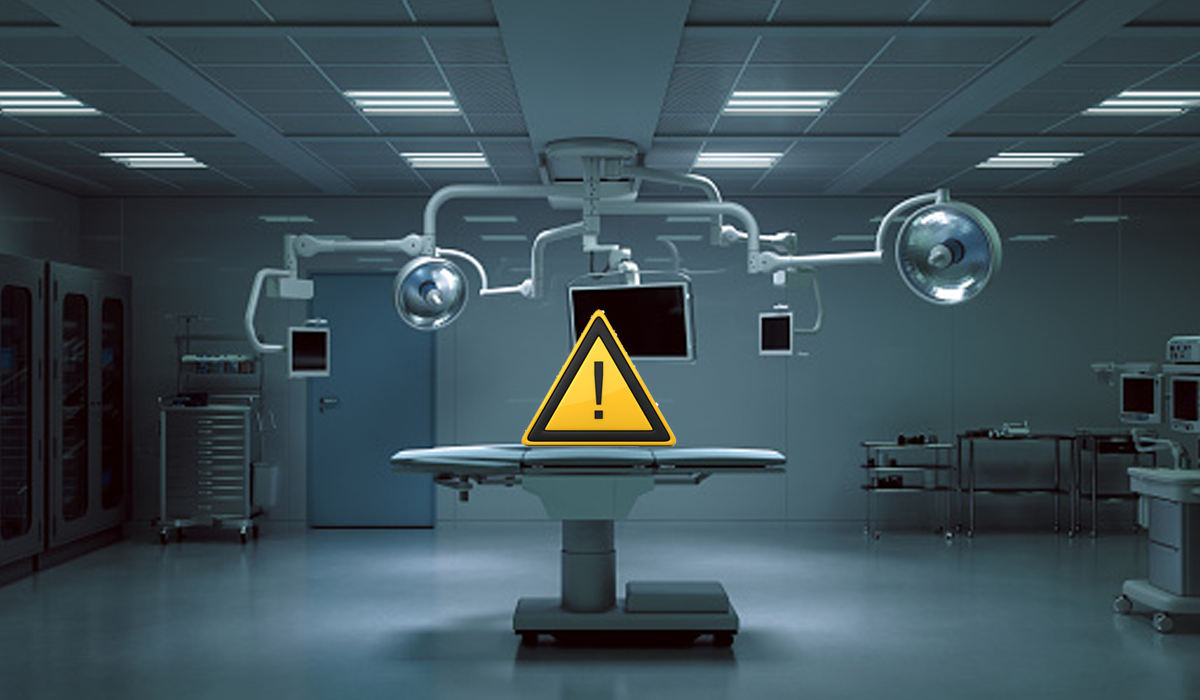 5 Health Care Workforce Shortage Takeaways for 2028. An empty operating room with a caution icon displayed above the table due to a shortage of health care workers.