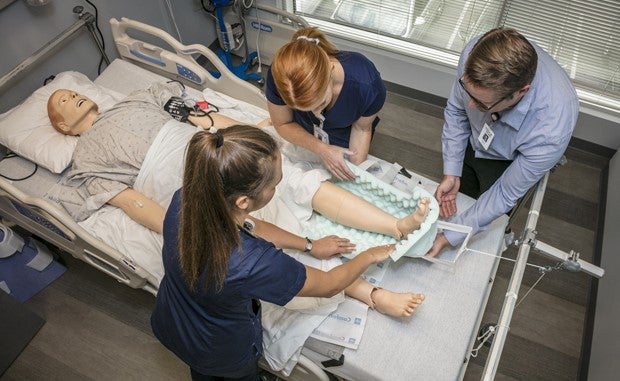 HCA Invests Heavily Again in Nurse Education and Training. An instructor trains two nurses using a medical dummy on a gurney.