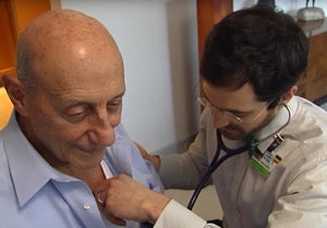 Doctor listening to elderly patient at home