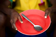 Blue Cross Blue Shield NC Pilot Programs Address Food Insecurity. A person of color holds out an empty bowl with the a spoon in the middle of it.