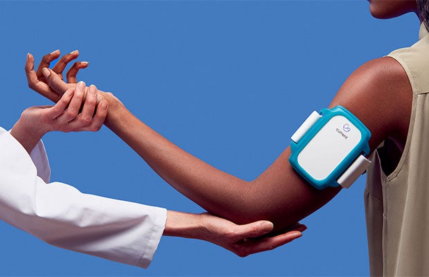 Combining Wearables and AI: A Value Play. Physician helps patient with wearable medical device extend his elbow.