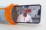 Is It Time to Partner with Retail Pharmacies on Service Expansion? A phone coming out of a prescription bottle with a female pharmacist on the screen.