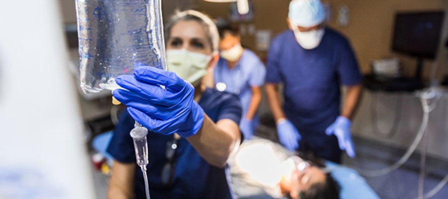 AHA Patient Safety Initiative Resources. In an operating room, a clinician adjusts an IV bag while other clinicians examine a patient.