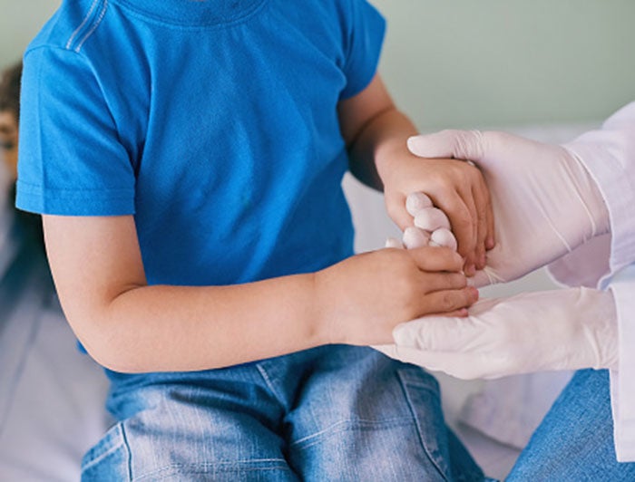 UC Davis Health doctors fashion a new upper arm from the collarbone for a young patient. A doctor wearing gloves holds the hands of a young patient to test the strength in his arms and hands.