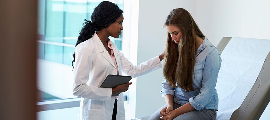 doctor consoling young woman in exam room