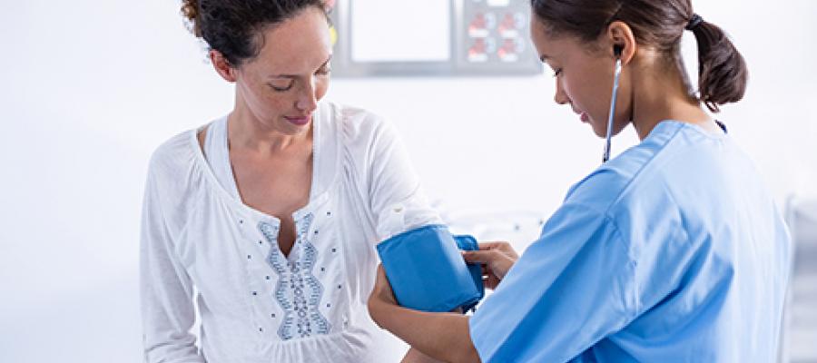 Maternal and Child Health - pregnant woman having blood pressure checked by female nurse