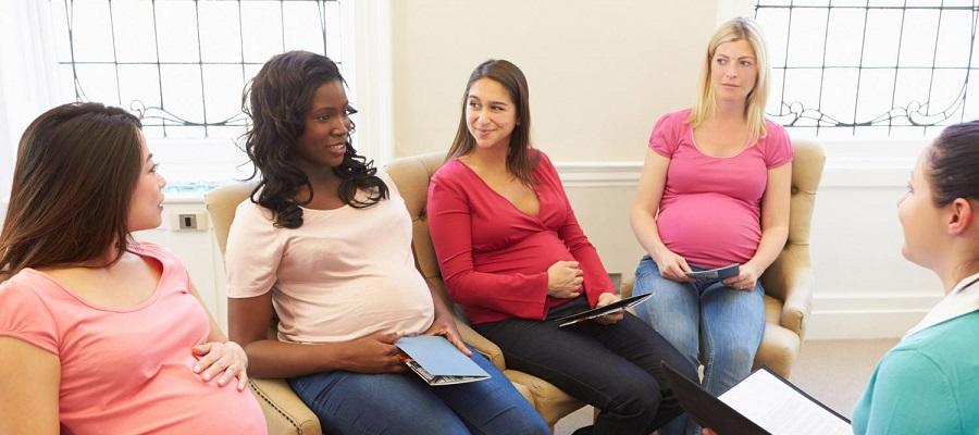 A diverse group of pregnant women in a maternity group information class speaking with a clinician.