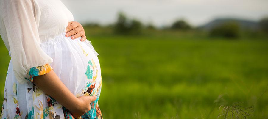 A-pregnant-woman-stands-in-a-meadow-clutching-her-pregnant-belly