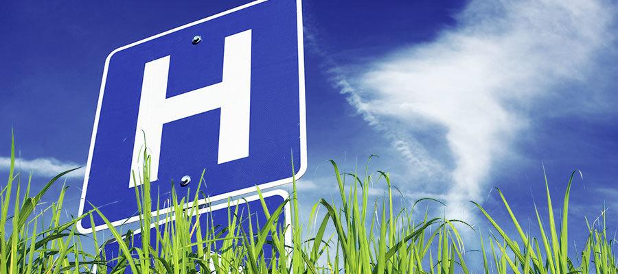 image of the hospital logo amid grass and a blue sky 