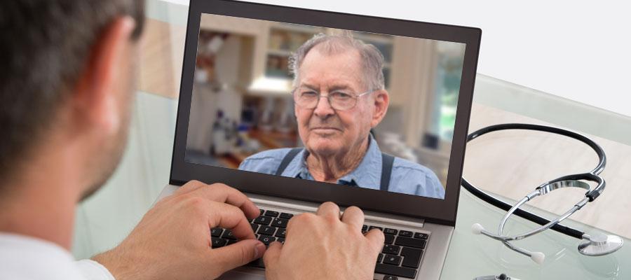 image of physician typing into a laptop with an image of man in suspenders on the screen