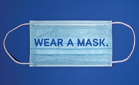 surgical mask on blue background with "wear a mask." superimposed on it.
