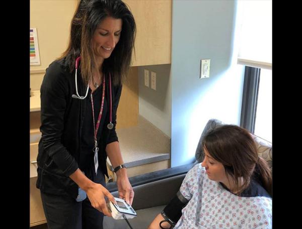 A female clinician stands measuring a mothers blood pressure in a clinical setting