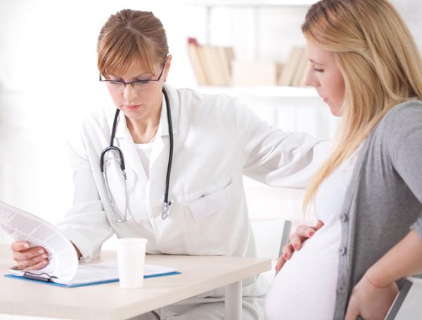 A female clinician sits reviewing notes with a pregnant woman