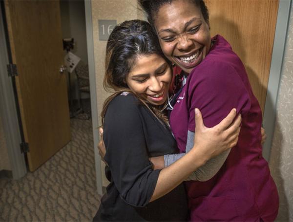 two women - a patient and a clinician - hug in hospital hallway